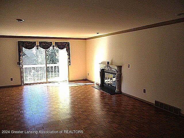 unfurnished living room with crown molding and parquet flooring