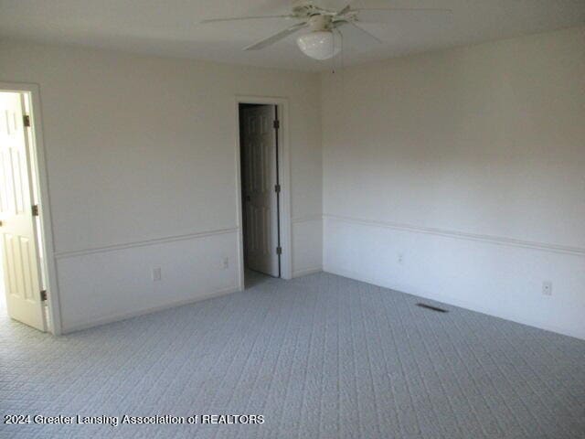 carpeted spare room featuring ceiling fan