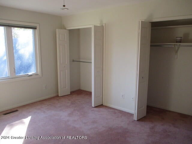 unfurnished bedroom with light carpet and a closet