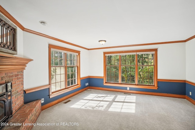 unfurnished living room featuring ornamental molding, a healthy amount of sunlight, a fireplace, and carpet floors