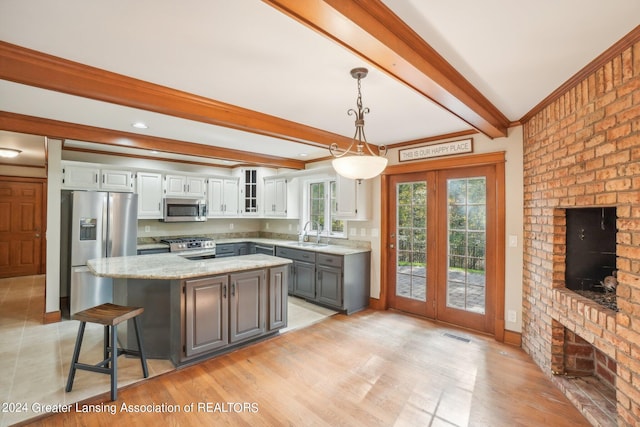 kitchen featuring white cabinets, beam ceiling, sink, appliances with stainless steel finishes, and a center island