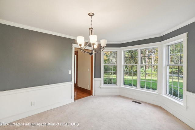 unfurnished dining area with ornamental molding, a chandelier, carpet, and a wealth of natural light