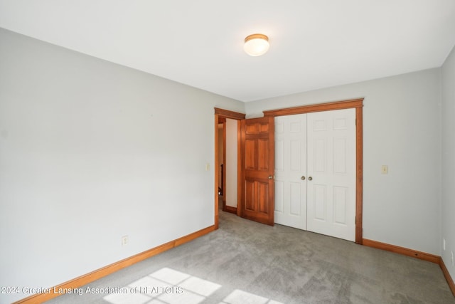 unfurnished bedroom with light colored carpet and a closet