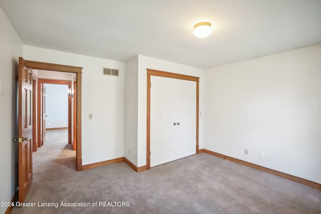 unfurnished bedroom featuring a closet and light colored carpet