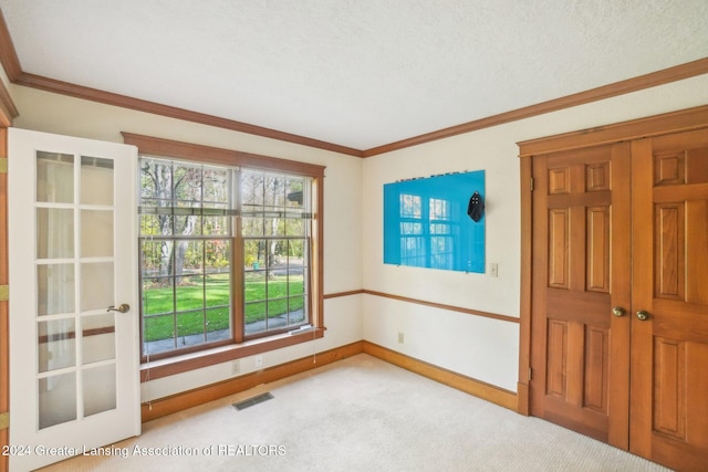 unfurnished room featuring light colored carpet, a textured ceiling, and crown molding