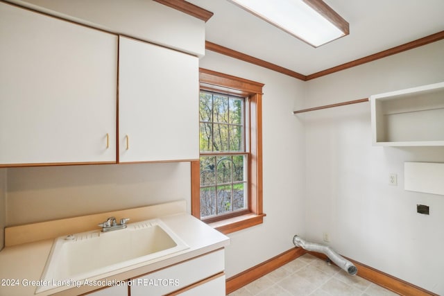 laundry room with ornamental molding, cabinets, and sink