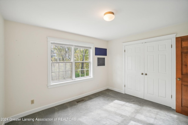 unfurnished bedroom with light colored carpet and a closet