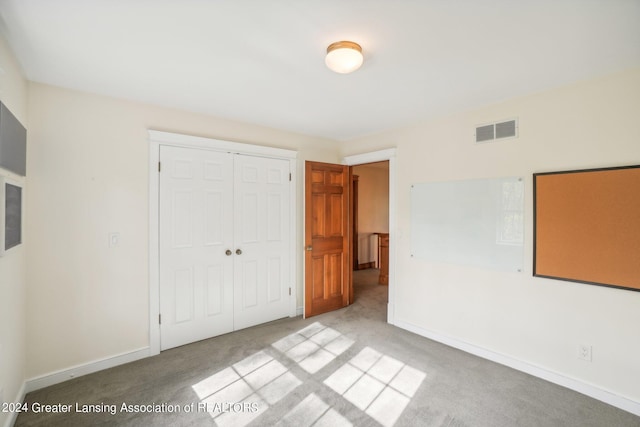 unfurnished bedroom featuring a closet and light colored carpet