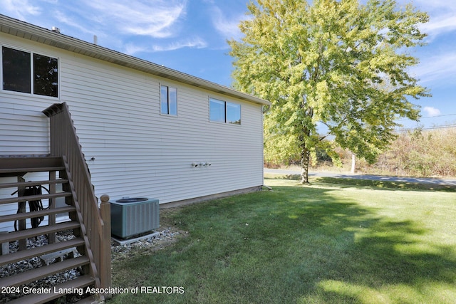 view of side of property with central AC and a yard