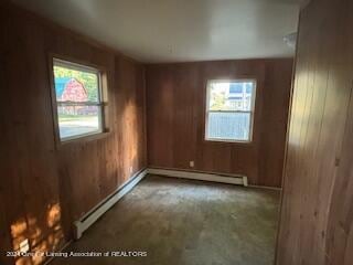 spare room featuring a baseboard radiator and wood walls