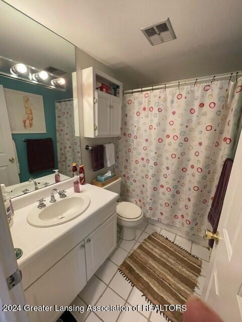 bathroom featuring toilet, curtained shower, vanity, and tile patterned floors