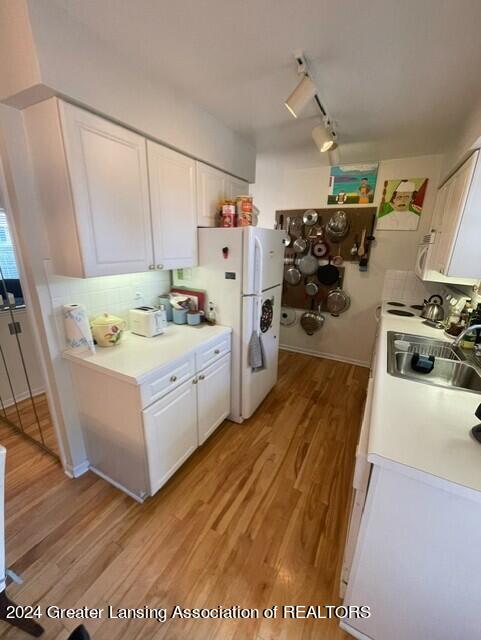 kitchen with rail lighting, white cabinetry, light hardwood / wood-style floors, white fridge, and sink