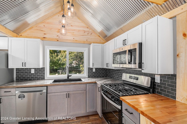 kitchen with white cabinetry, stainless steel appliances, wood counters, and sink