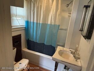 bathroom featuring shower / bath combination with curtain and toilet