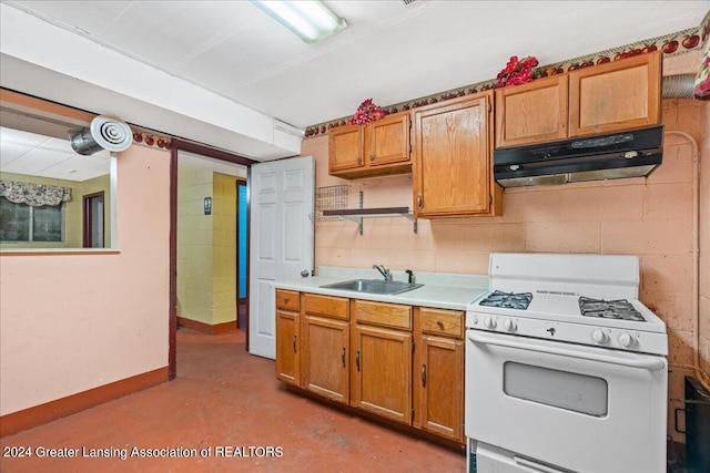 kitchen featuring white range with gas stovetop, sink, and concrete flooring