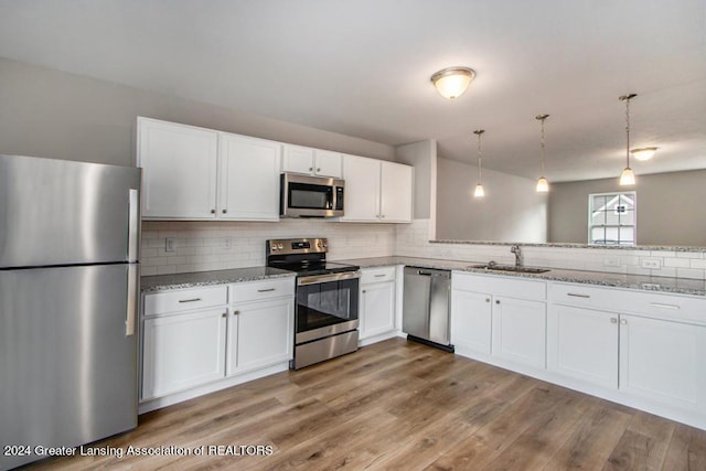 kitchen featuring appliances with stainless steel finishes, pendant lighting, white cabinets, and sink