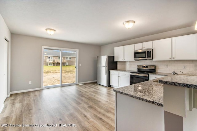 kitchen with stainless steel appliances, decorative backsplash, dark stone countertops, white cabinets, and sink