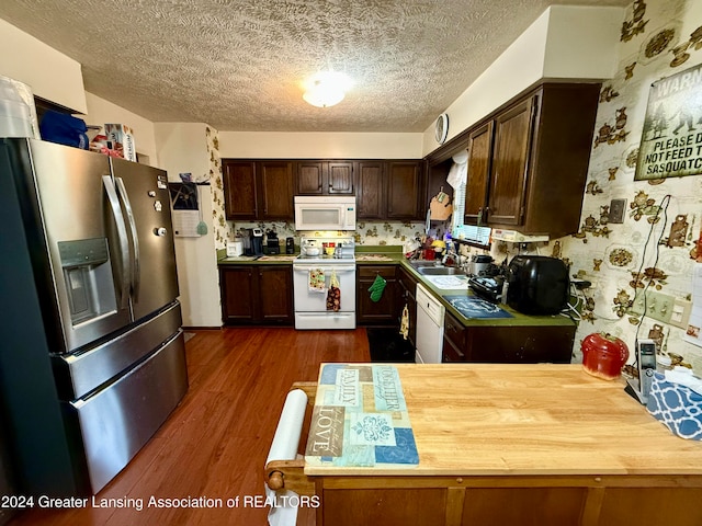 kitchen featuring dark brown cabinetry, sink, a textured ceiling, dark hardwood / wood-style flooring, and white appliances