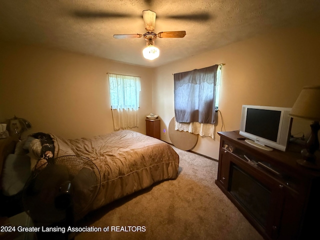 bedroom featuring light carpet, a textured ceiling, and ceiling fan