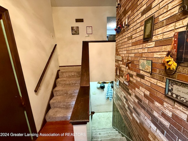 staircase featuring brick wall