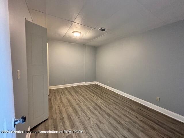 empty room featuring a drop ceiling and hardwood / wood-style flooring