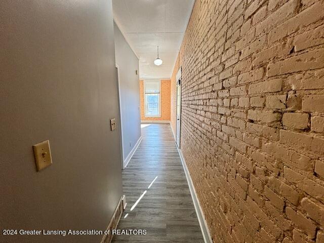 hall with brick wall and dark hardwood / wood-style flooring