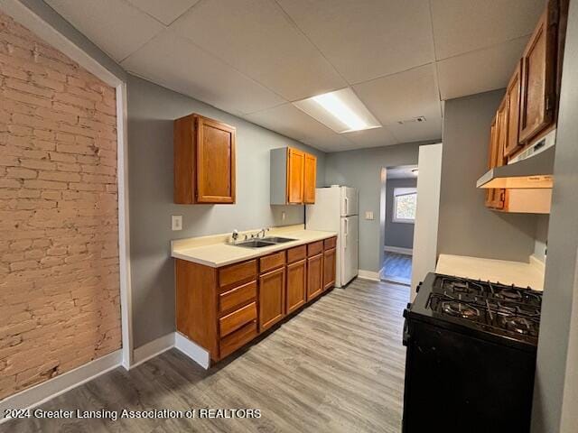 kitchen featuring light hardwood / wood-style flooring, white fridge, sink, and black range with gas cooktop