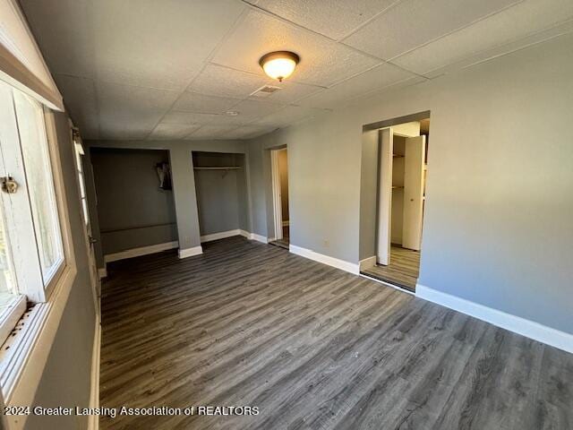 unfurnished bedroom with a drop ceiling and dark hardwood / wood-style floors