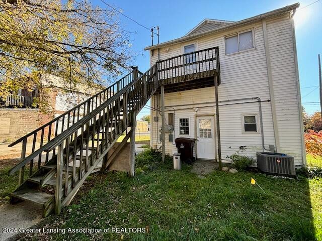 back of property with central air condition unit and a lawn