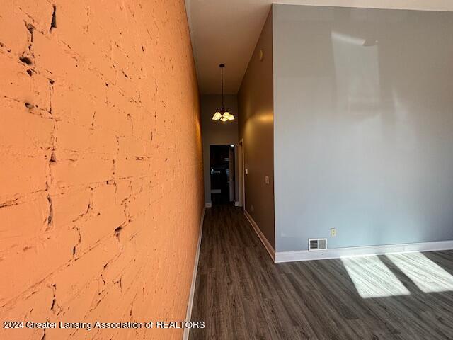 hallway with dark hardwood / wood-style floors and a chandelier