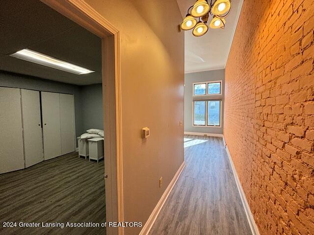 corridor featuring brick wall and dark hardwood / wood-style flooring