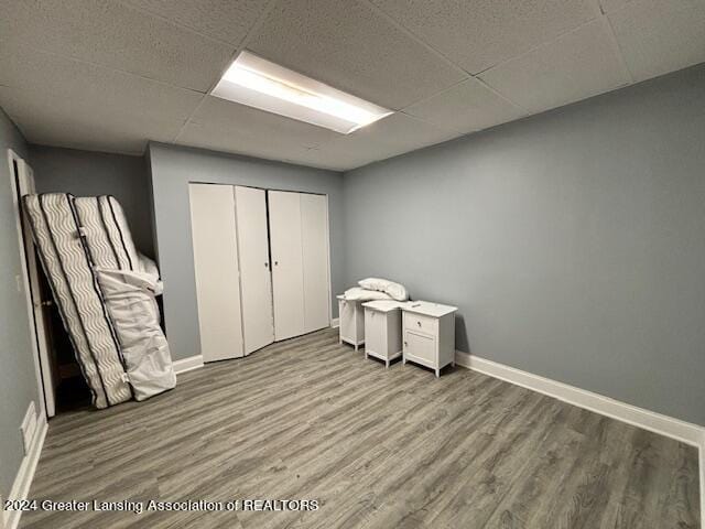 unfurnished bedroom featuring a closet, a paneled ceiling, and wood-type flooring