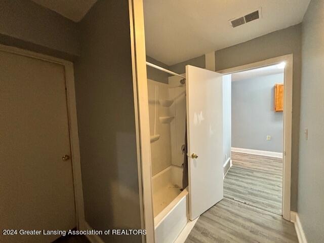 bathroom with wood-type flooring and  shower combination