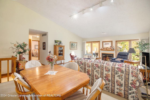 dining area featuring high vaulted ceiling and light colored carpet