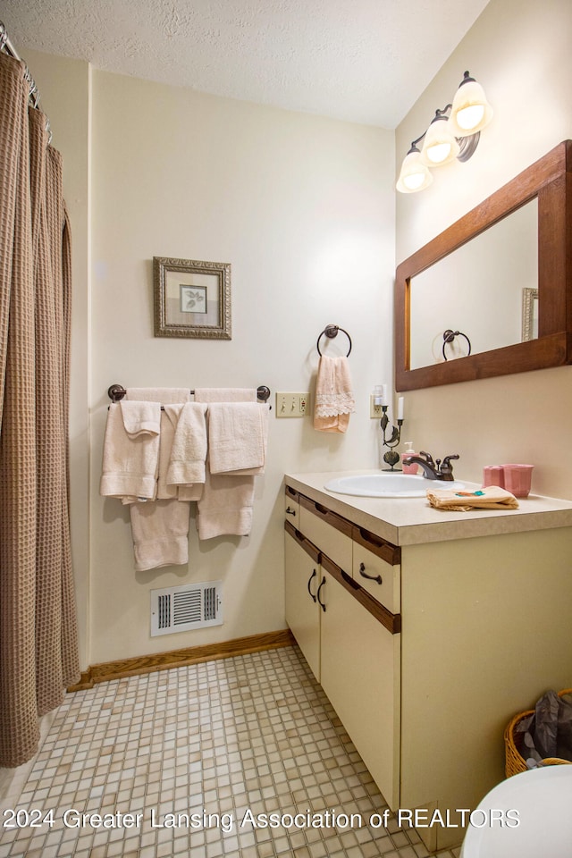 bathroom with vanity, toilet, and a textured ceiling