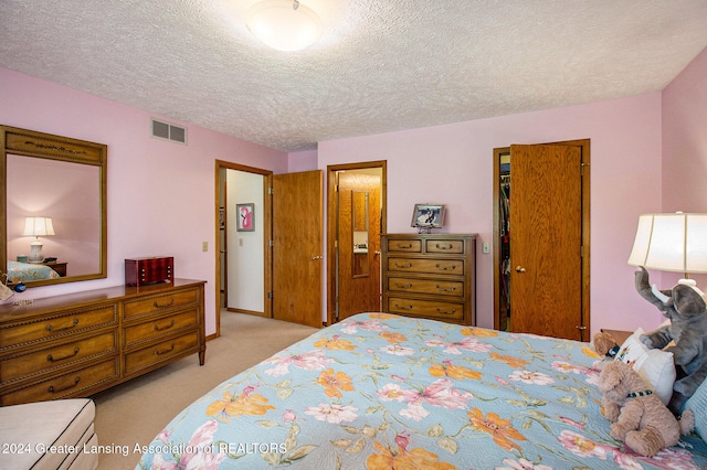 bedroom with a textured ceiling, light colored carpet, and a closet