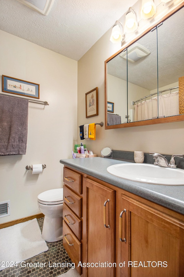 bathroom with vanity, a textured ceiling, toilet, and tile patterned flooring