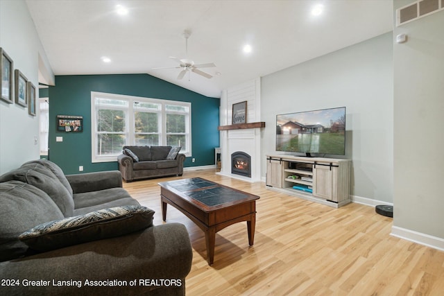 living room with vaulted ceiling, a fireplace, hardwood / wood-style flooring, and ceiling fan