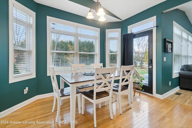 dining room with vaulted ceiling, a notable chandelier, and hardwood / wood-style flooring