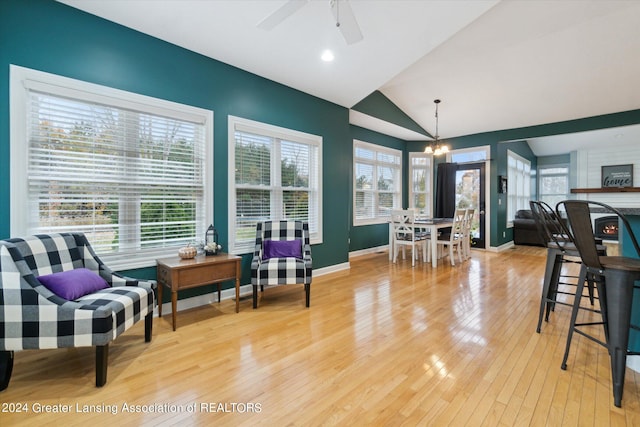 living area with a healthy amount of sunlight, light wood-type flooring, and vaulted ceiling