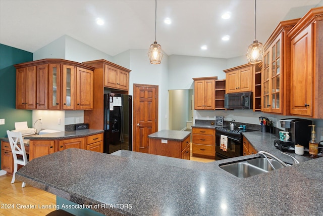 kitchen featuring lofted ceiling, black appliances, hanging light fixtures, and sink