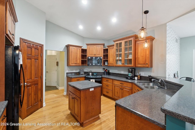 kitchen featuring black appliances, sink, light wood-type flooring, a kitchen island, and hanging light fixtures