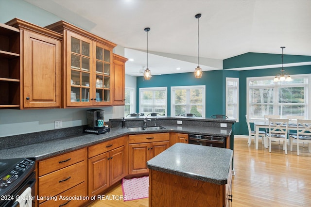 kitchen featuring lofted ceiling, a center island, sink, and light wood-type flooring