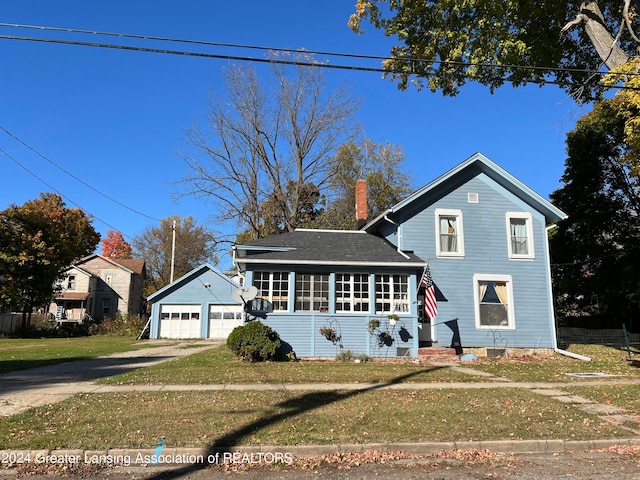 view of front facade featuring a front yard, a garage, and an outbuilding