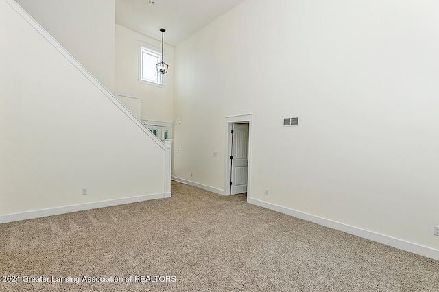 unfurnished living room featuring carpet and a towering ceiling