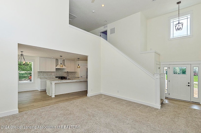 unfurnished living room with light carpet and a high ceiling