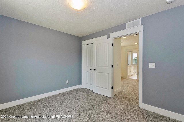 unfurnished bedroom featuring a textured ceiling, a closet, and carpet flooring