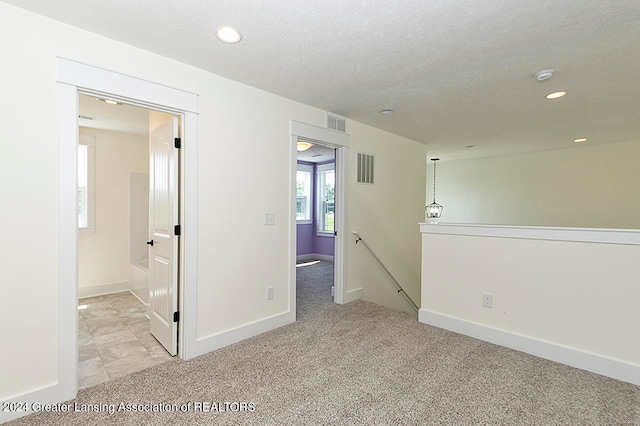 interior space featuring light colored carpet and a textured ceiling