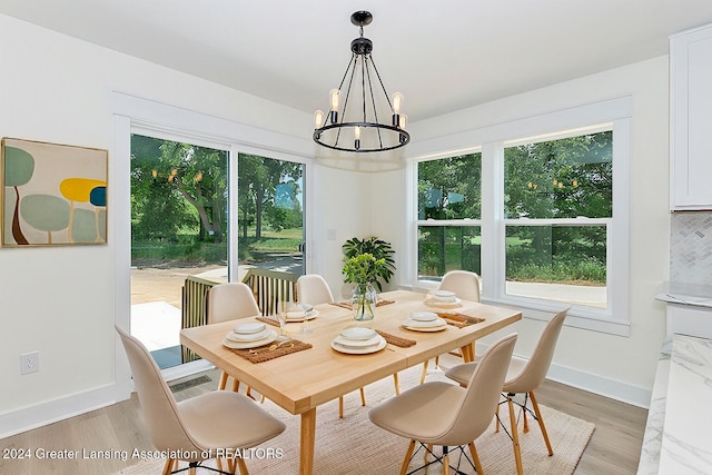 dining space with a wealth of natural light, a chandelier, and light hardwood / wood-style flooring