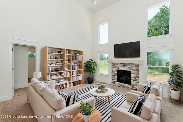 carpeted living room featuring a high ceiling and a fireplace